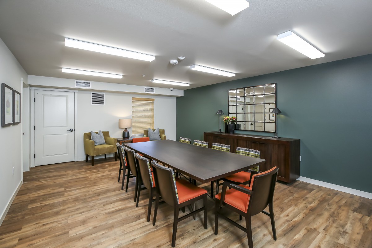 A modern conference room with a large meeting table and chairs, featuring stylish decor and lighting.