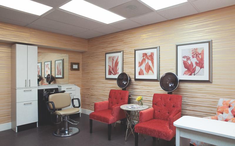 A cozy salon interior featuring red chairs, wall art, and hair dryers.