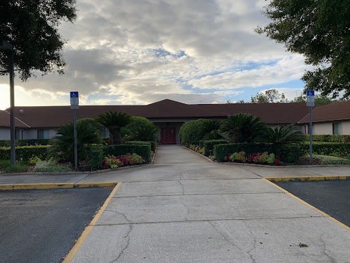 Entrance to a serene building surrounded by greenery under a cloudy sky.