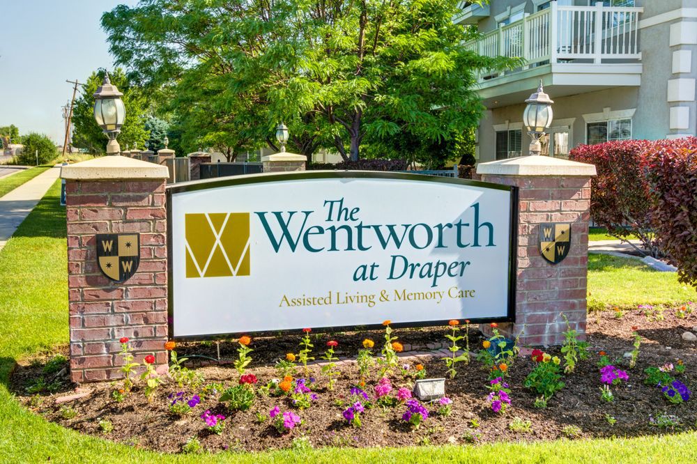 The Wentworth at Draper assisted living facility entrance sign surrounded by flowers and greenery.