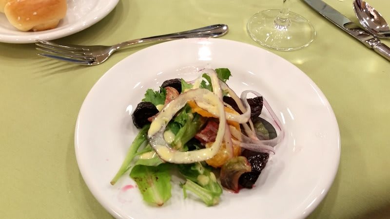 A fresh salad with beets, onions, and lettuce served on a white plate.
