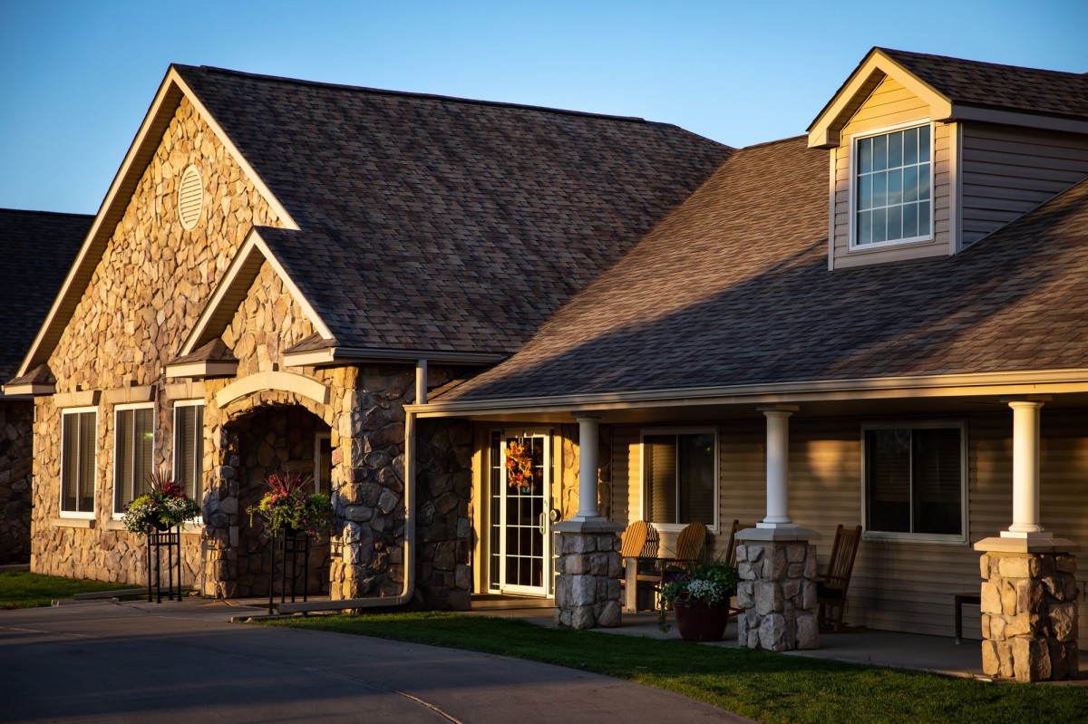 A charming house with a stone facade and a welcoming front porch, basking in warm sunlight.