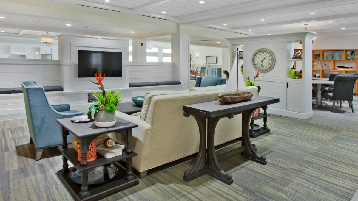A well-decorated living room featuring a cozy sofa, a TV on the wall, decorative plants, and elegant furniture.