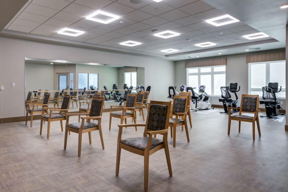 An indoor gym with chairs arranged in rows and various exercise equipment.