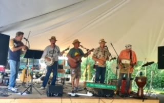 A band performing on stage under a tent.