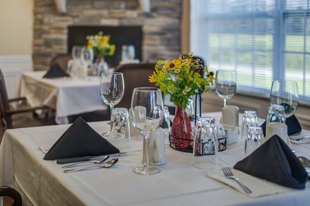 A beautifully set table in a fine dining restaurant with flowers and elegant glassware.