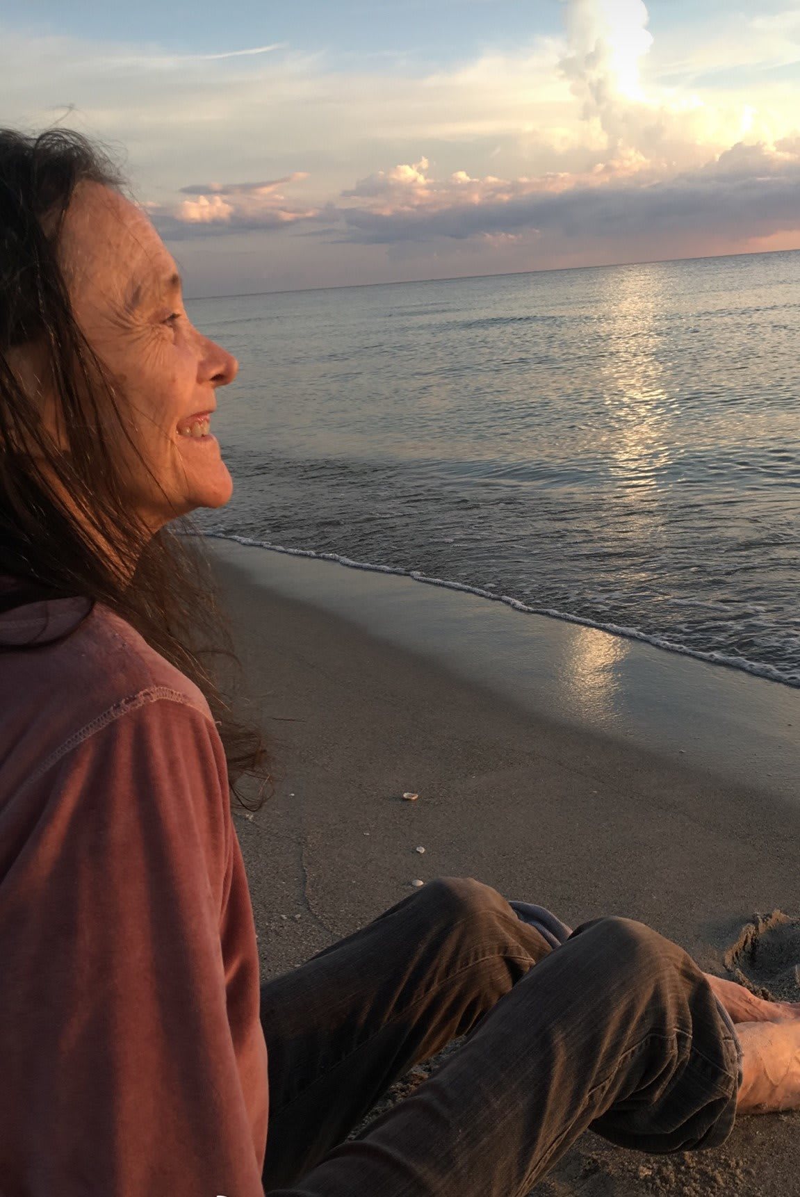 A woman enjoys a peaceful sunset by the ocean.