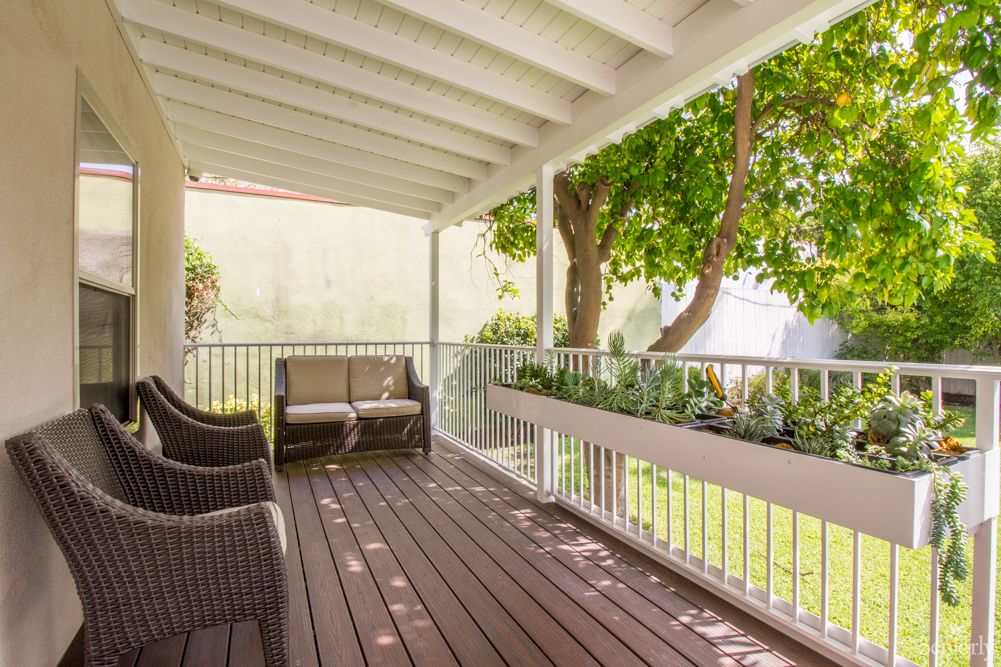 A cozy outdoor deck with seating overlooking a lush garden.