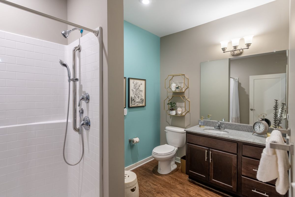 A modern bathroom featuring a shower, toilet, and vanity with a large mirror.