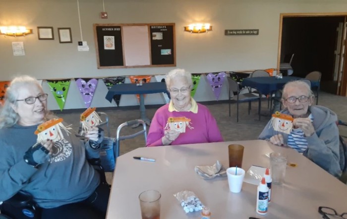A group of elderly people enjoying a crafts activity in a decorated room.