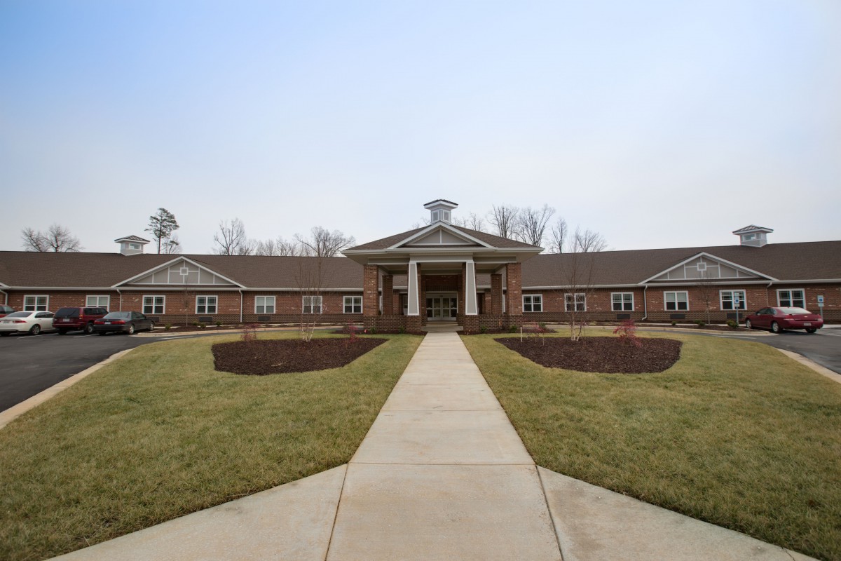 A symmetrical brick building with a central entrance and landscaped pathway.
