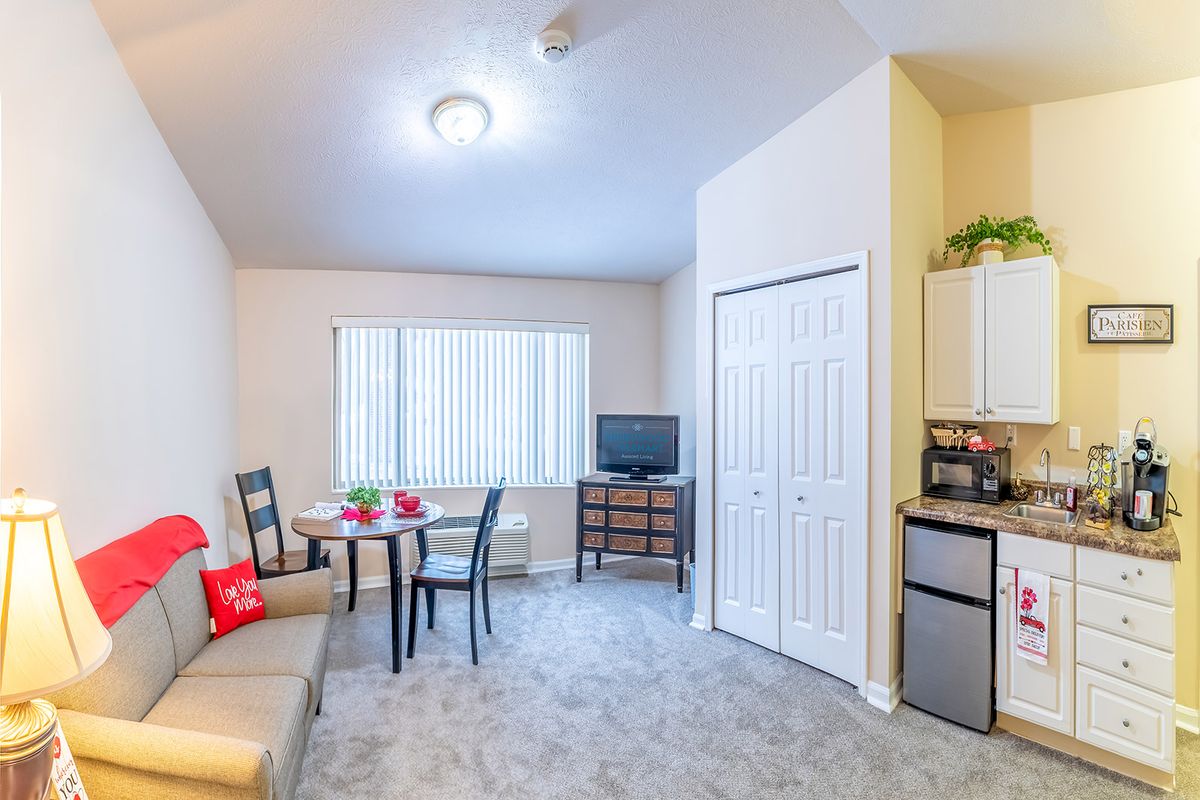 A cozy apartment living area with a small dining table, chairs, and a TV.