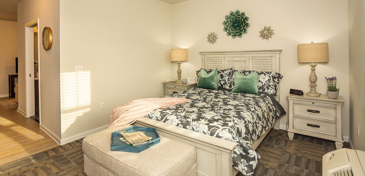 A cozy bedroom with patterned bedding, decorative pillows, and soft lighting.