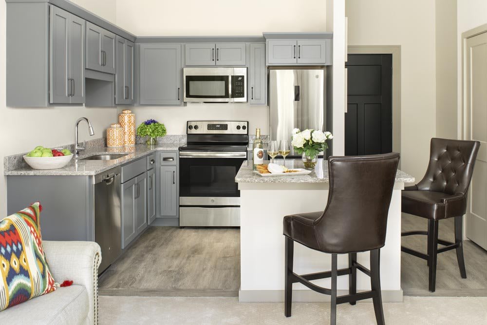 A modern kitchen with gray cabinets and stainless steel appliances.