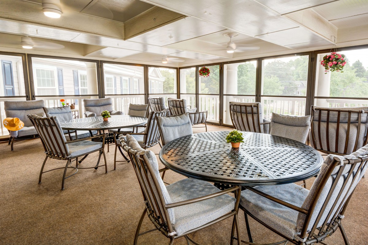 An indoor patio area with tables and chairs, offering a view through large glass windows.