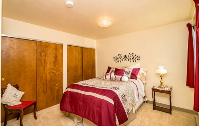 A cozy bedroom with a neatly made bed, closet doors, and decorative wall art.