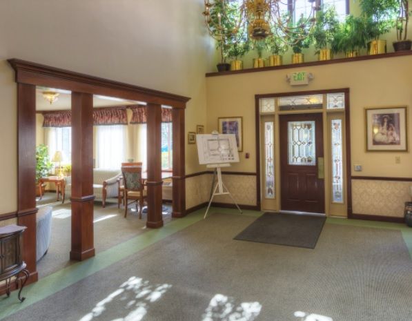 A well-lit lobby with wooden accents, plants, and an entrance door.