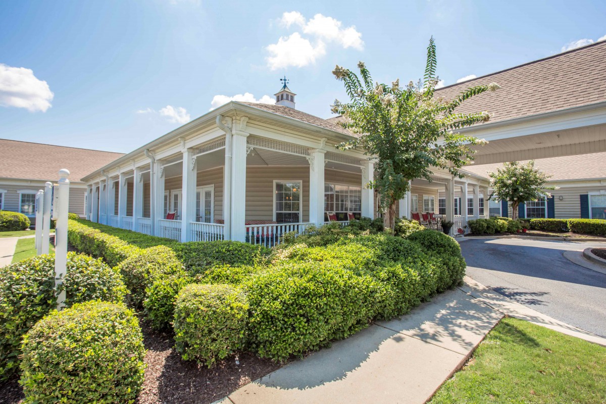 A sunny day view of a building with a covered porch and well-maintained landscaping.