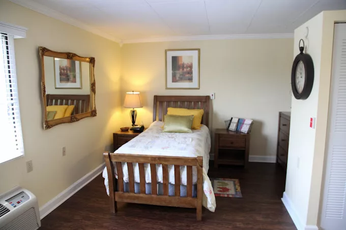 A cozy bedroom with a single bed, wooden furniture, and soft lighting.