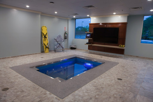 A stylish indoor pool integrated into a modern living space, featuring blue lighting and contemporary decor.
