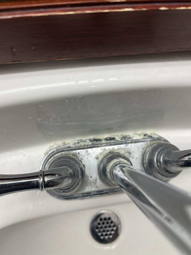 Close-up of a bathroom sink faucet with visible mold and grime.