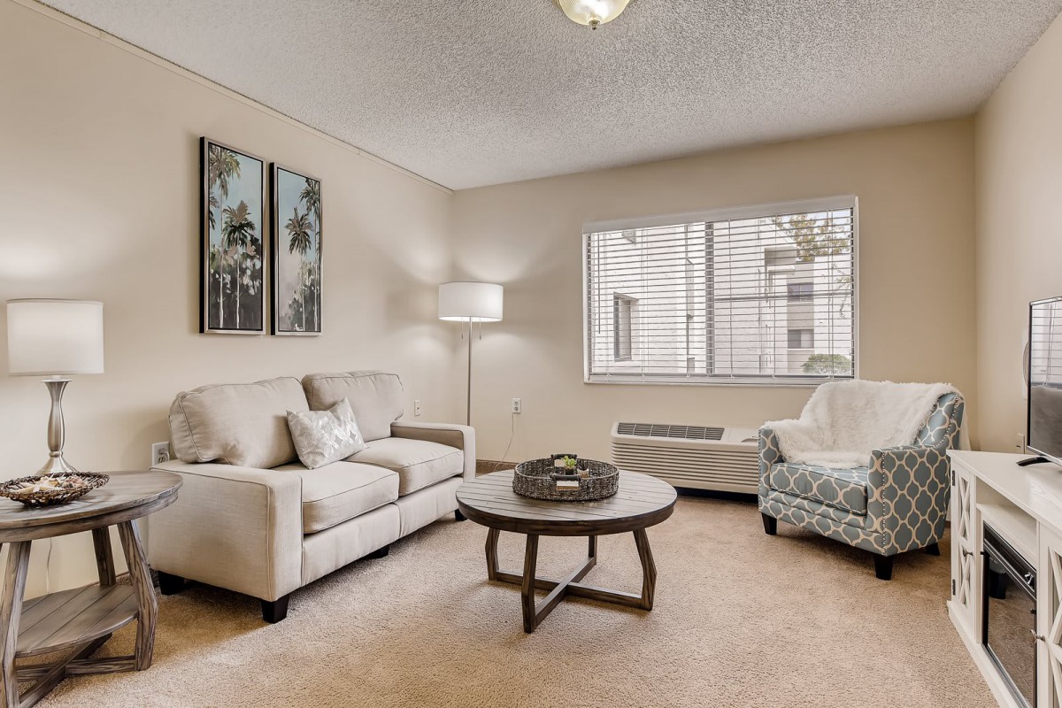 A cozy living room with neutral tones featuring a sofa, armchair, and coffee table.