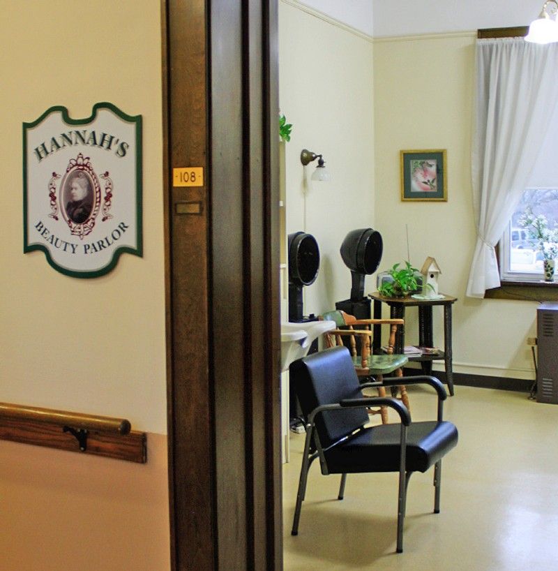 A cozy hair salon interior with chairs and mirrors, featuring decorative plants and soft lighting.