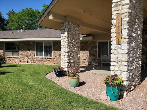 A cozy home entrance featuring stone columns and colorful planters.