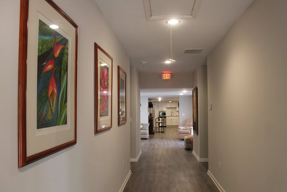 A brightly lit hallway adorned with framed artwork on the walls.