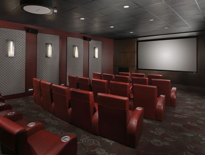 A cozy home theater with comfortable red seating and a large screen.