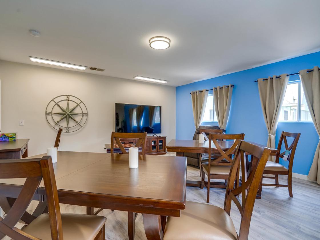 A spacious living and dining area with wooden furniture, featuring a TV and decorative wall elements.