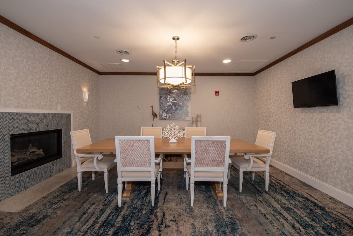 A stylish dining room featuring a large wooden table with six chairs, a modern chandelier, and artistic wall decor.