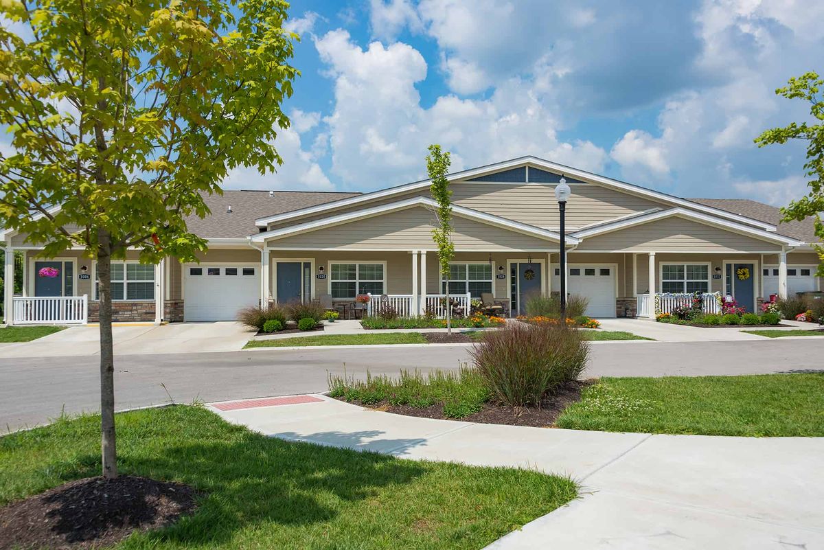 A suburban residential building surrounded by a landscaped front yard and clear skies.