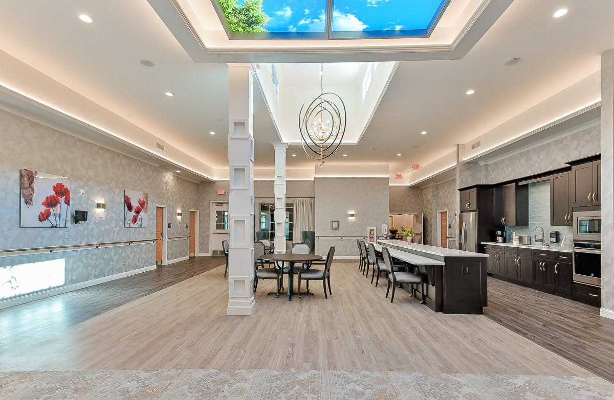 A modern open-plan kitchen and dining area with a large skylight and elegant lighting fixture.