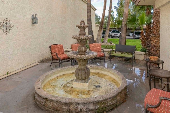 A stone fountain in a patio area with seating.