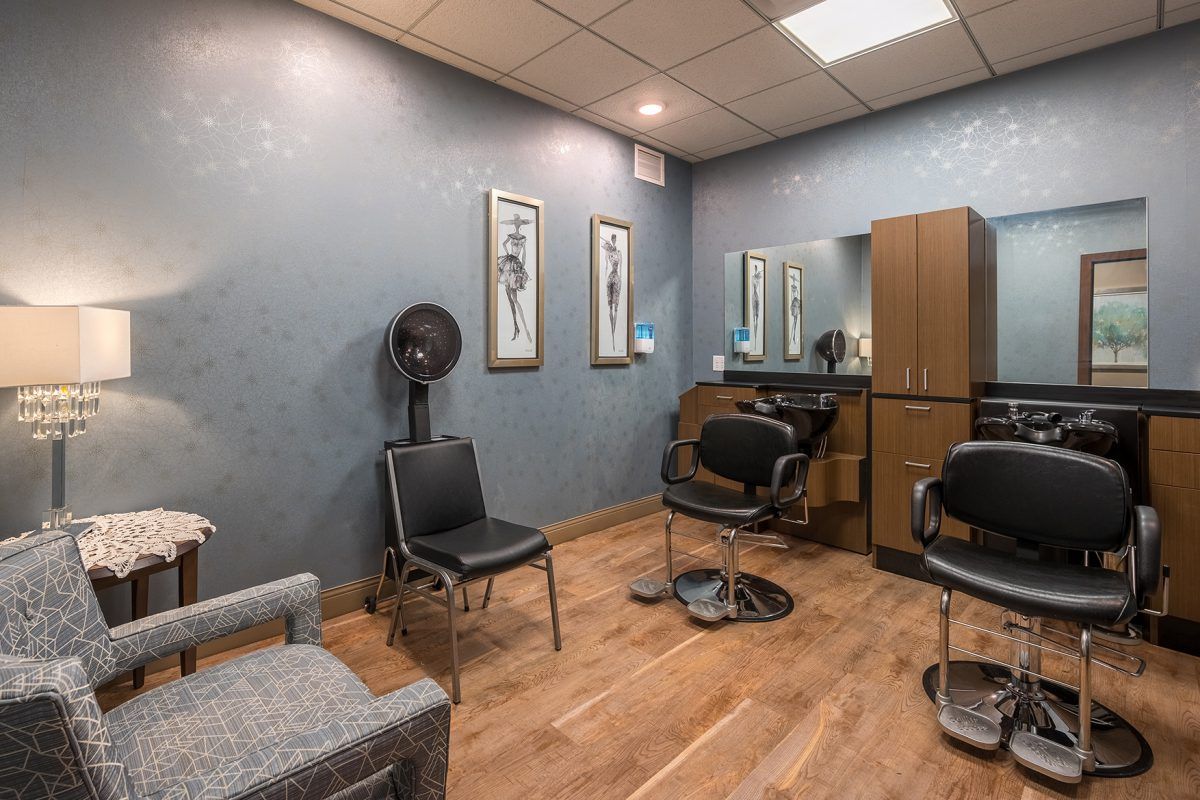A cozy hair salon interior with styling chairs and a large mirror.