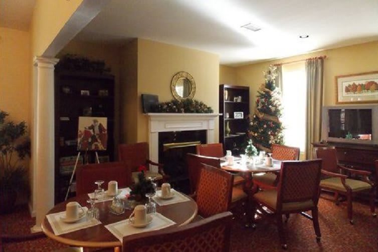 A cozy dining room decorated for the holidays with a set table and a Christmas tree near the fireplace.