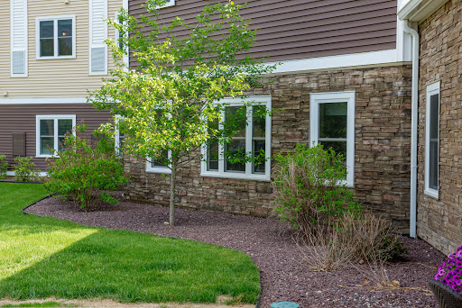 A beautiful residential building with a stone facade, featuring lush greenery and well-maintained landscaping.