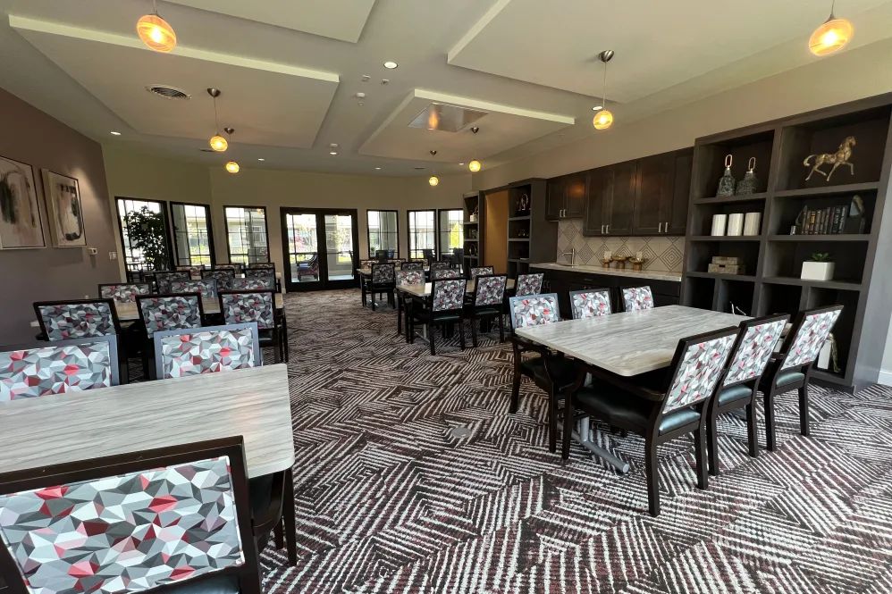 A modern dining room with patterned carpeting and stylish chairs arranged around tables.