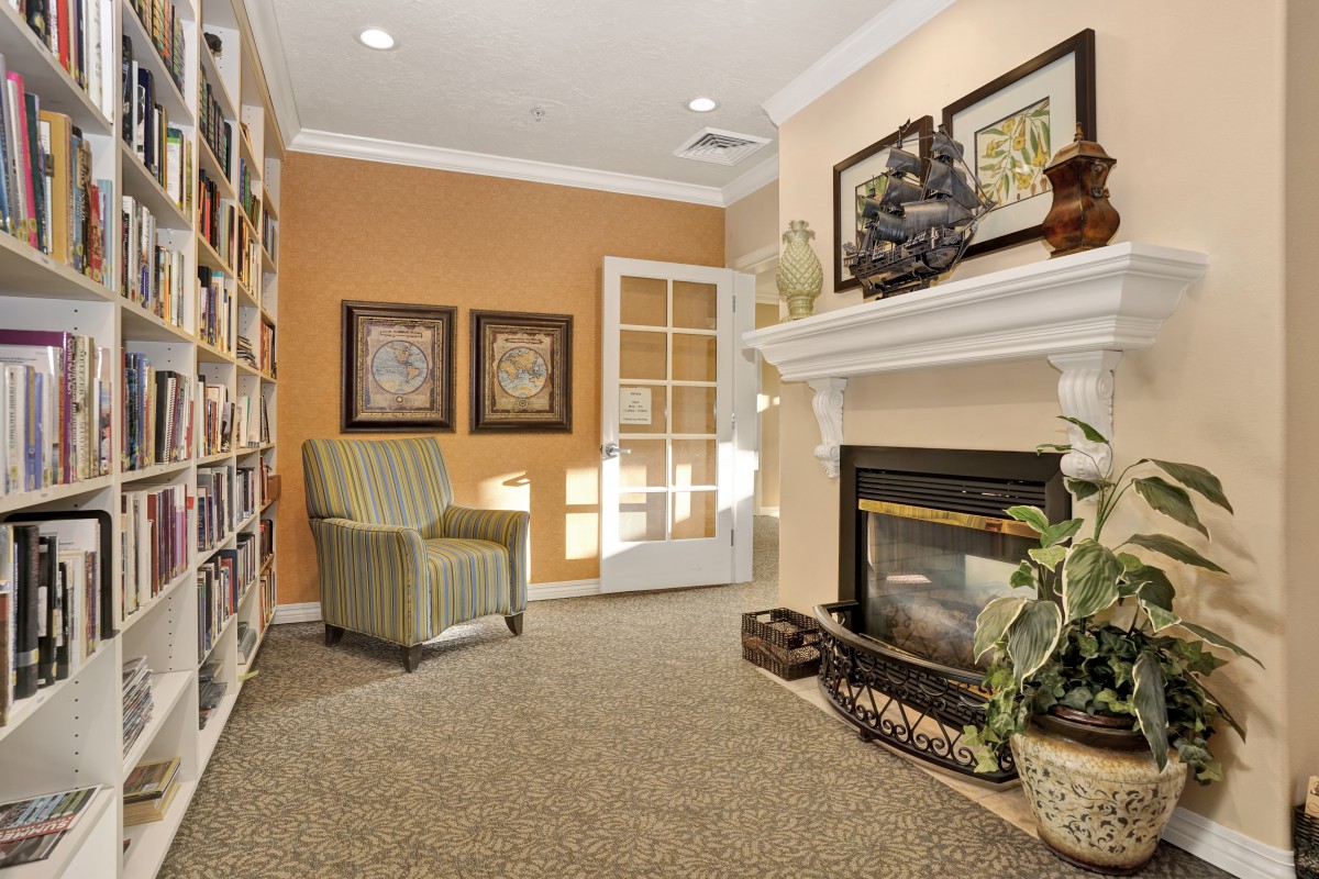 A cozy living room featuring a warm fireplace, comfortable armchair, and a well-stocked bookshelf.