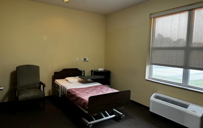 A simple hospital room with a single bed and window.
