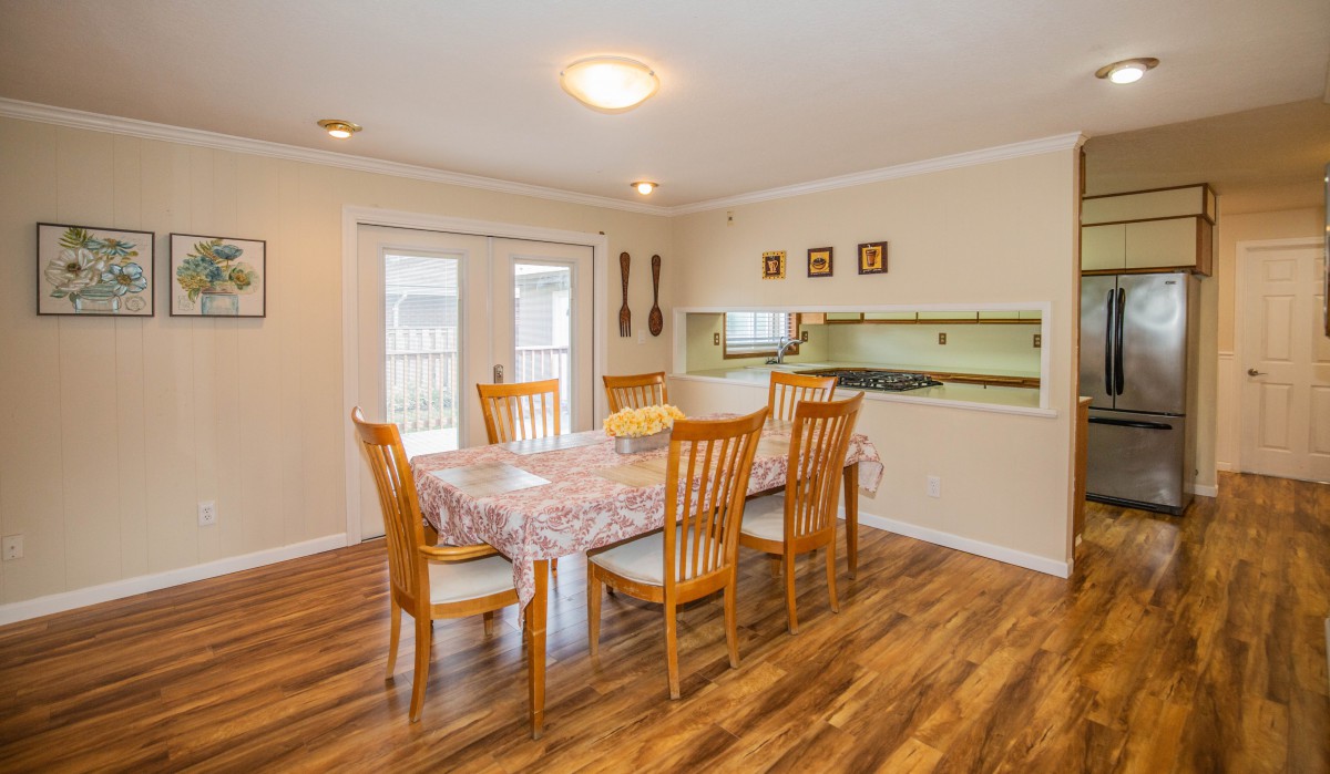 A cozy dining room with a wooden floor and a large dining table surrounded by chairs.