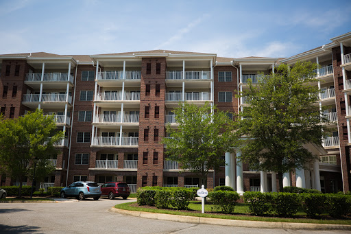 A modern residential building featuring multiple balconies and surrounded by greenery.
