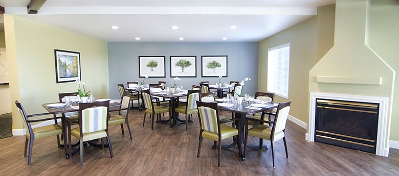 A well-arranged dining room with several tables and chairs, decorated with framed artworks on the wall.