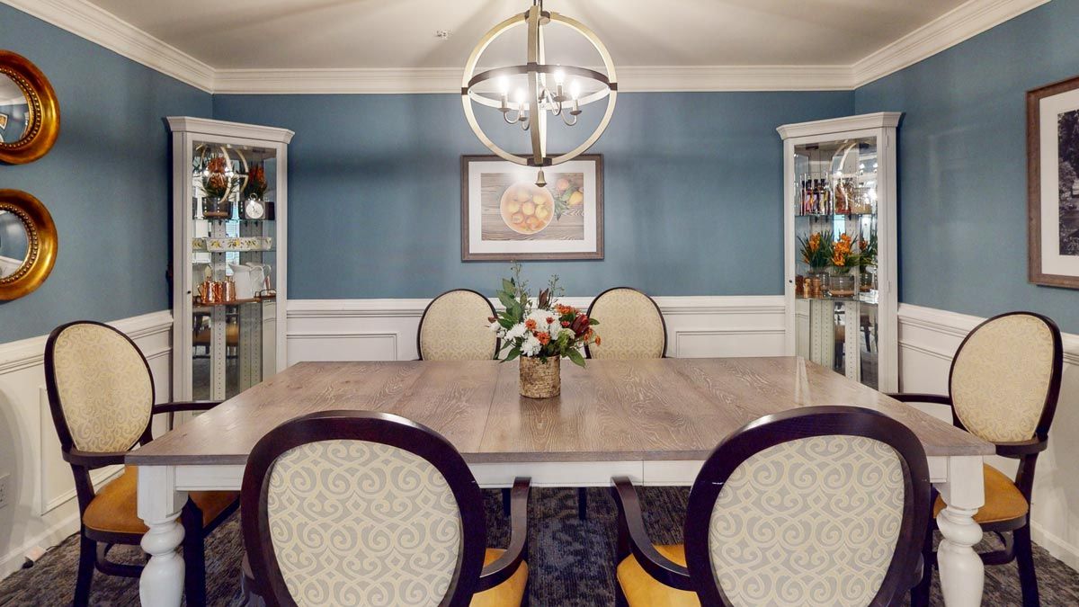 A stylish dining room with a central table, elegant chairs, and a modern chandelier.