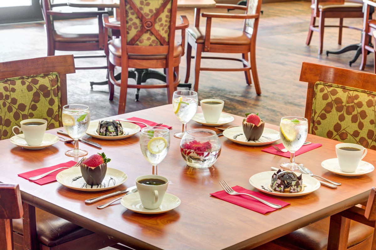 A beautifully set table in a restaurant featuring an assortment of cupcakes, coffee cups, and water glasses.