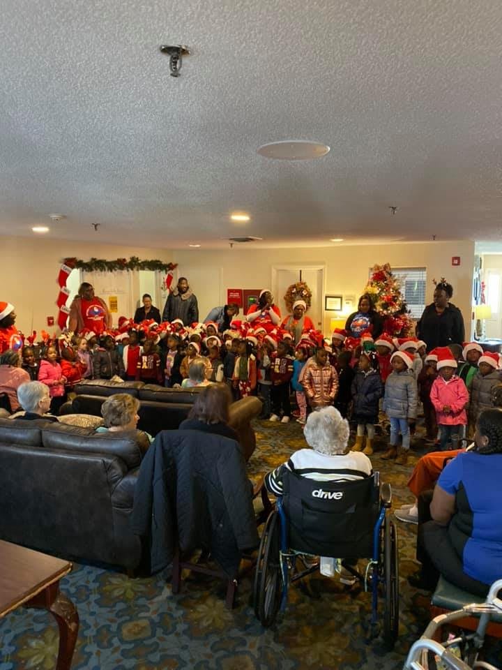 Children perform a holiday program for seniors in a festive setting.