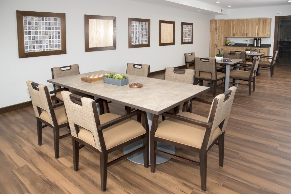 A modern dining area featuring a large table with chairs, adjacent to a kitchen.