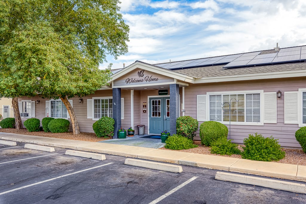 A commercial office building with an entrance surrounded by landscaping and a parking lot.