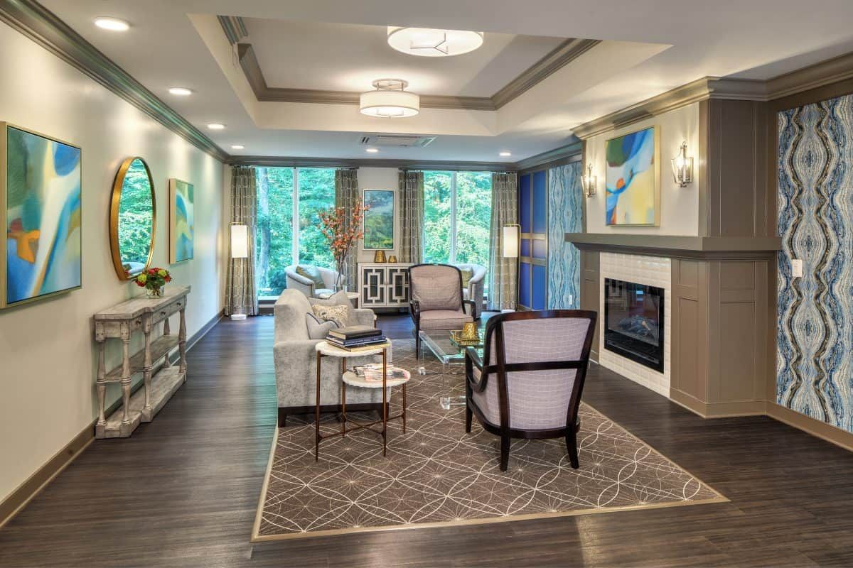 A modern living room with stylish furniture, a fireplace, and large windows overlooking greenery.